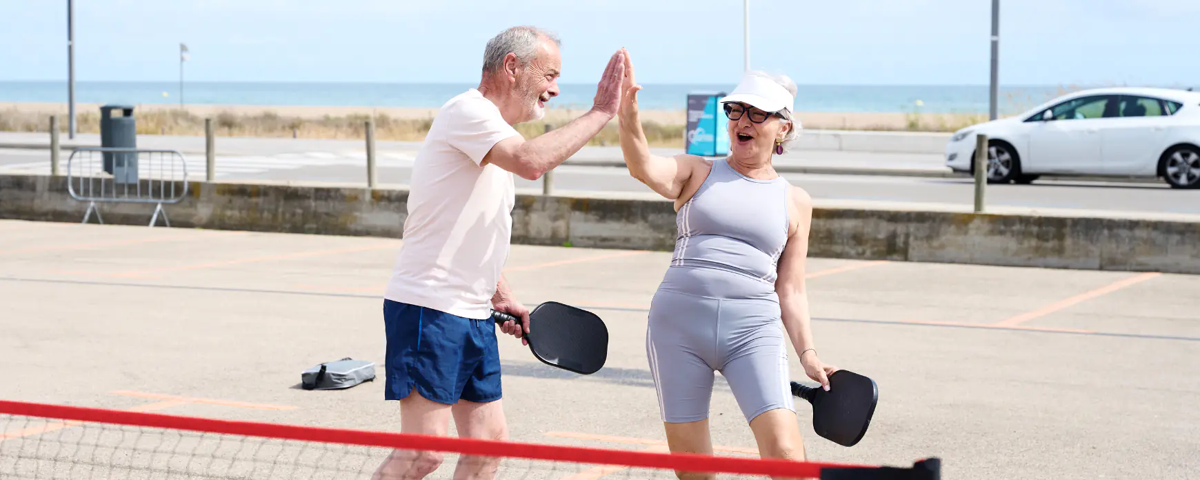 Casal sénior ativo a celebrar enquanto joga padel.